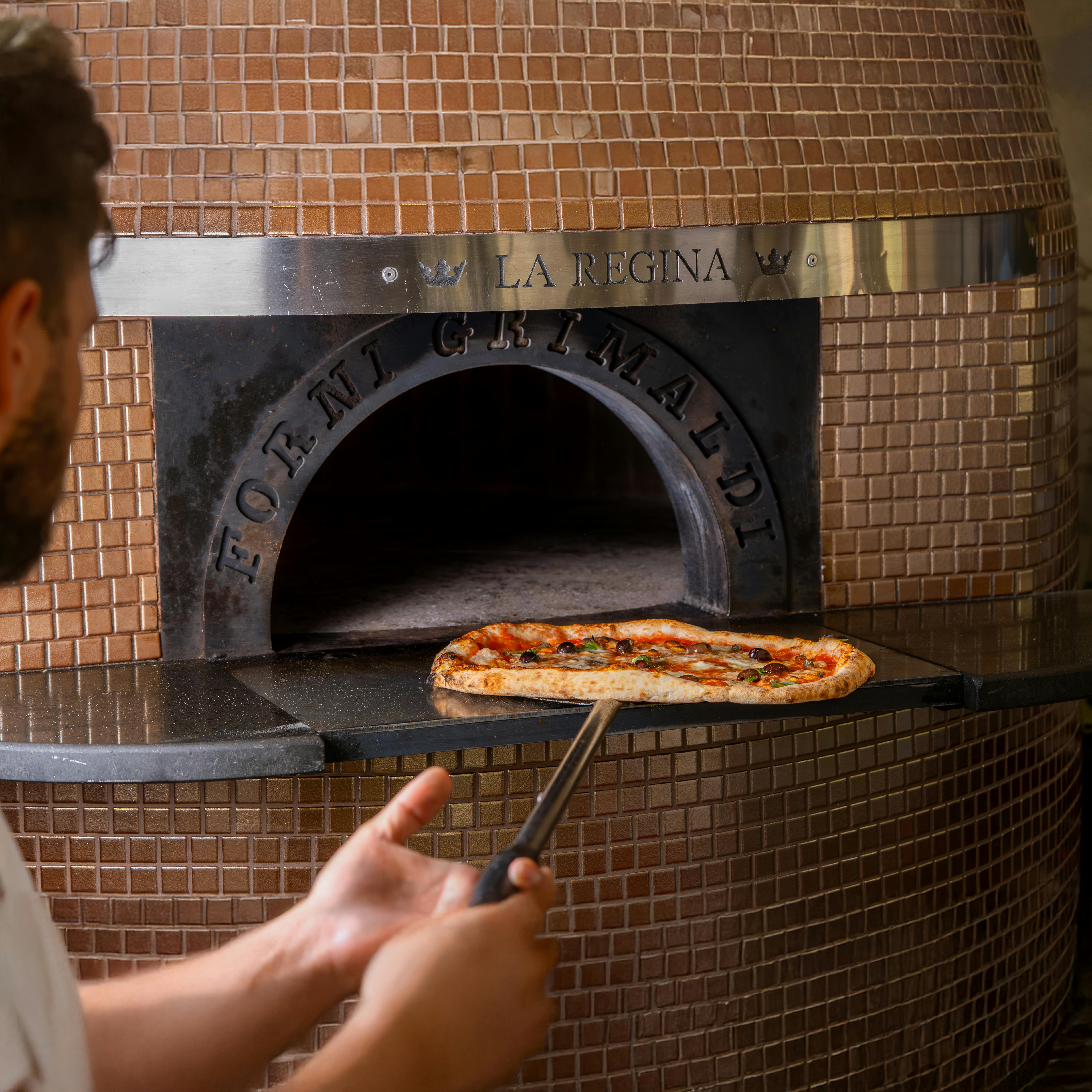 Pizza sendo preparada e assada na hora